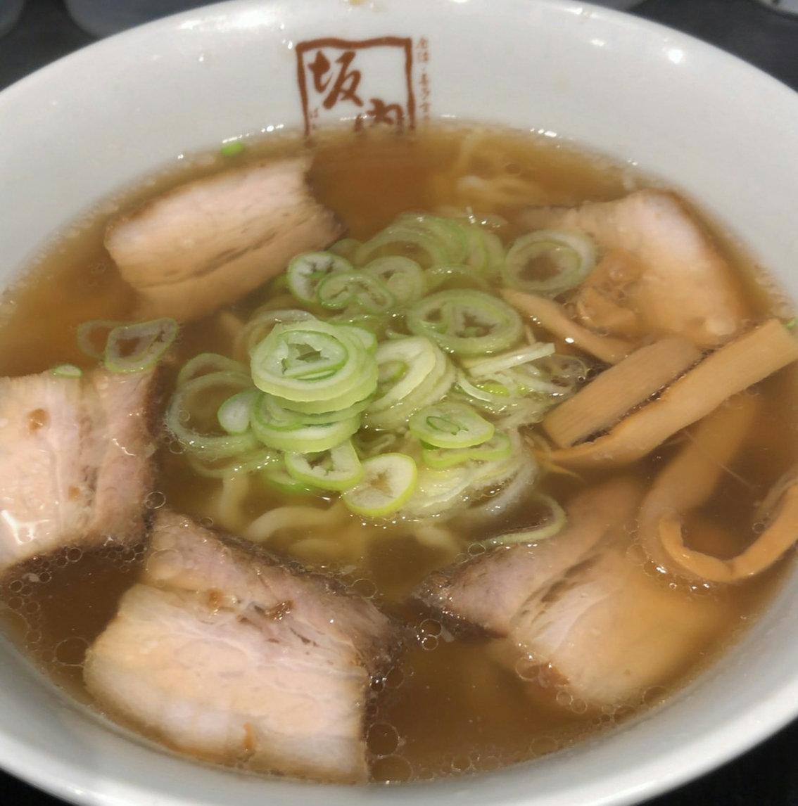 A bowl of Kitakata-style shoyu ramen with chashu, green onions, and bamboo shoots at Bannai.