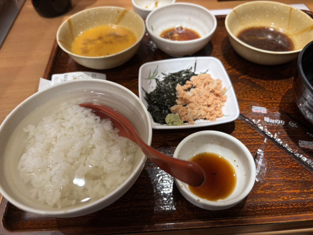 A bowl of dashi chazuke with flaked salmon, nori, and condiments at Yayoi Ken.