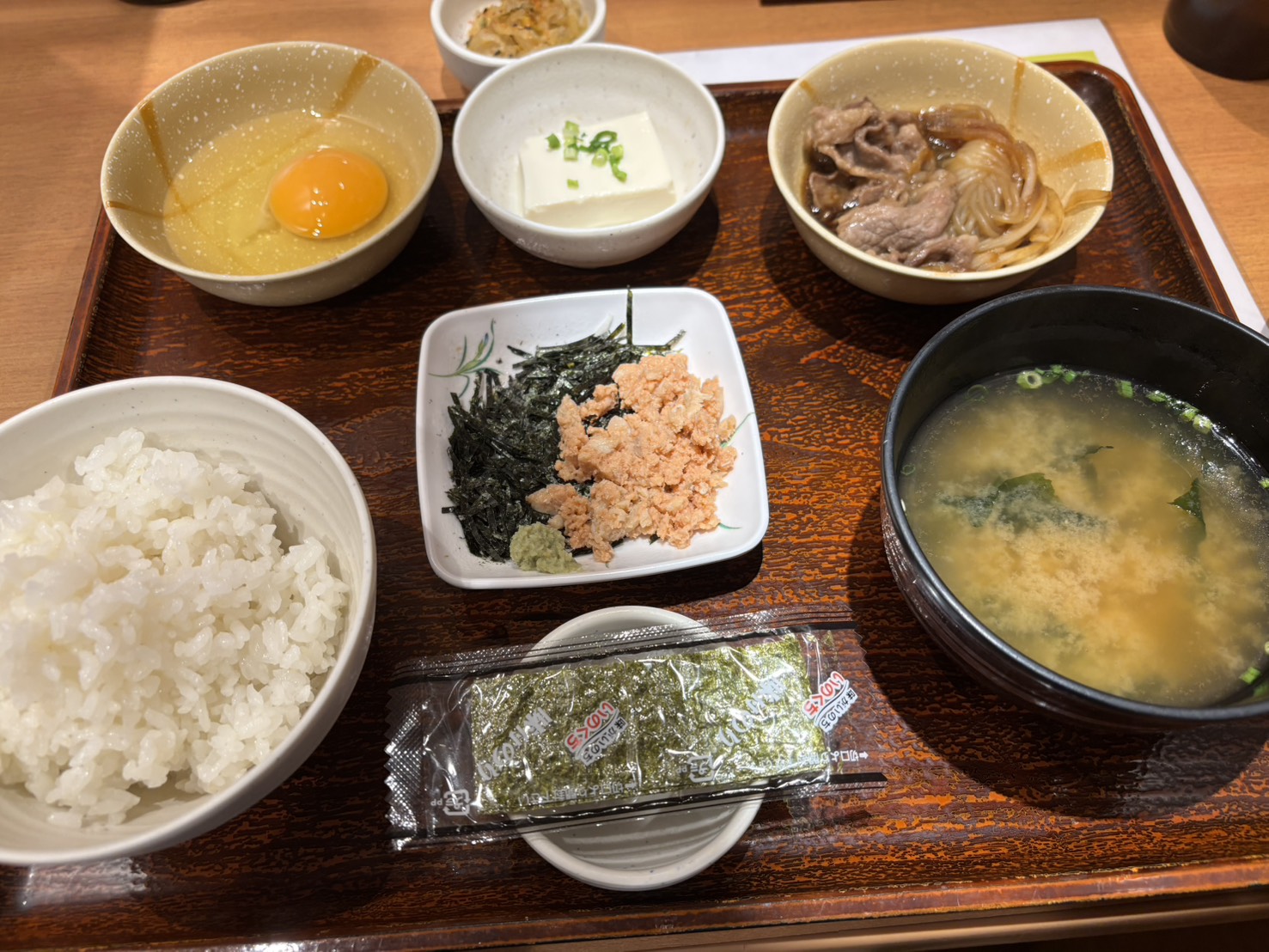 Yayoi Ken Mini Sukiyaki Breakfast with rice, miso soup, raw egg, tofu, mini sukiyaki, and flaked salmon.
