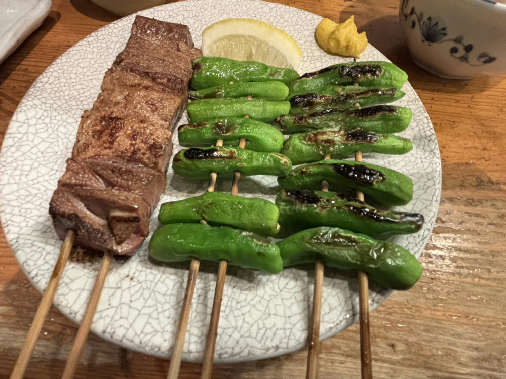 ALT: Grilled liver and shishito pepper skewers at Mitsumasa in Shimbashi, Tokyo, served with lemon and mustard.